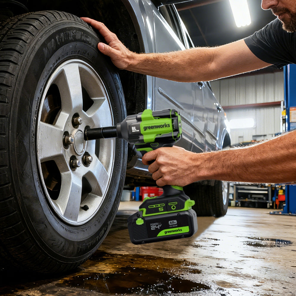 Person using a Greenworks power tool to work on a tire in a garage.