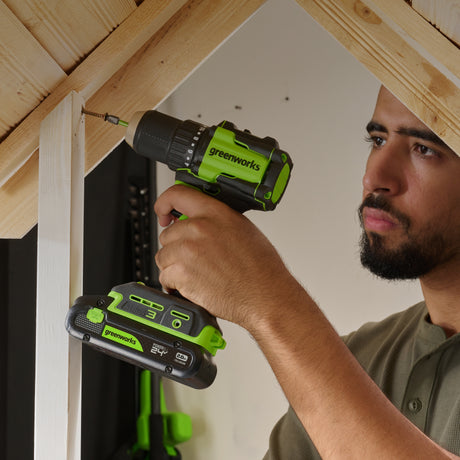 Person using a Greenworks power drill on a wooden structure