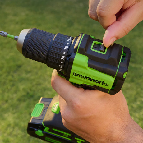 Hand holding a Greenworks drill with a green background