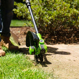 Person using a green and black lawn edger on grass