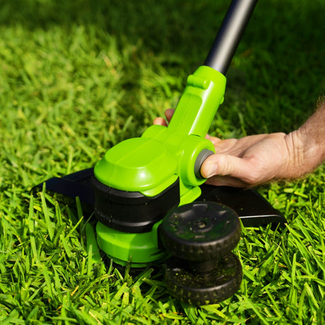 Person using a green lawn edger on grass