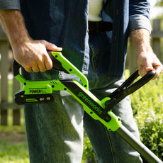 Person holding a greenworks power tool outdoors