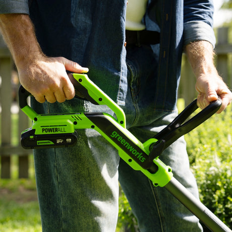 Person holding a greenworks power tool outdoors
